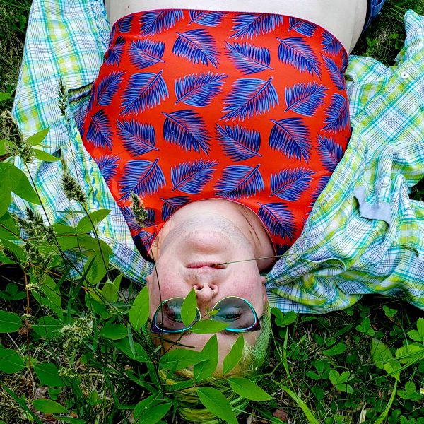 Eli wearing a Palmistry binder while lying on the grass.